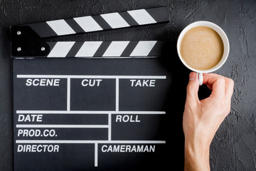 Screenwriter desktop with movie clapper board dark background top view