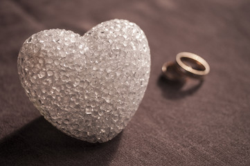 Love, wedding and Valentine`s day concept. Beautiful golden wedding rings and glass heart selective focus. useful as greeting card