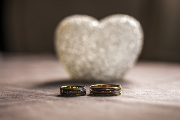 Love, wedding and Valentine`s day concept. Beautiful golden wedding rings and glass heart selective focus. useful as greeting card