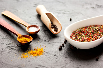 spices in wooden spoon on dark background