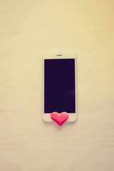 Top view on smart phone and love hearts on wooden desk background. Flat lay style copy space closeup image