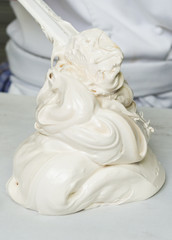 A beautiful rich and creamy , white whipped meringue mixture being scooped out onto a kitchen surface.
