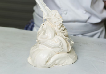A beautiful rich and creamy , white whipped meringue mixture, being scooped out onto a kitchen surface.