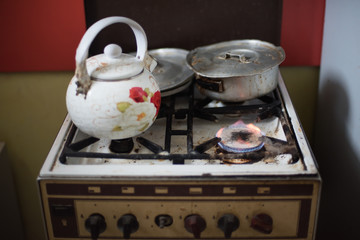 Old cooker with kitchenware a lit the burner, vintage effect