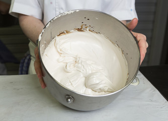 A beautiful rich and creamy , white whipped meringue mixture in a large metal mixing bowl.