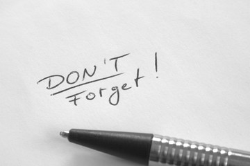 Fototapeta premium Don't Forget reminder note in hand writing on white paper