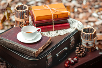 Old suitcase with old books and cup of tea on brown background