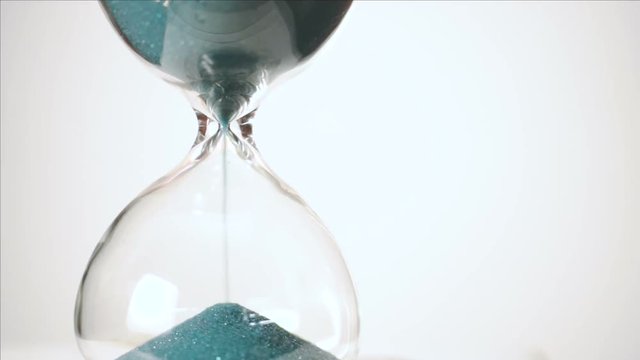 Sand falls signifying time passing in the hourglass