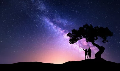 Abwaschbare Fototapete Nacht Milchstraße mit Menschen unter dem Baum auf dem Hügel. Landschaft mit nächtlichem Sternenhimmel und Silhouette von stehenden glücklichen Männern und Frauen, die mit dem Finger in den Sternenhimmel zeigen. Milchstraße mit Reisenden. Universum