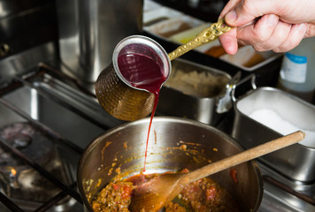 Sweet blended pomegranate sauce being poured into a hot frying pan of ingredients