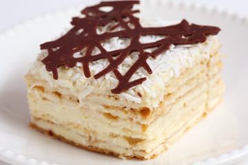 isolated slice of decorated with chocolate napoleon cake, served on white plate

