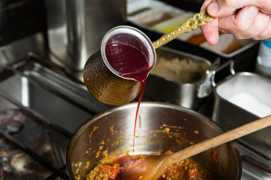 Sweet blended pomegranate sauce being poured into a hot frying pan of ingredients