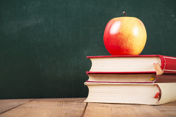 school books and apple against blackboard with 