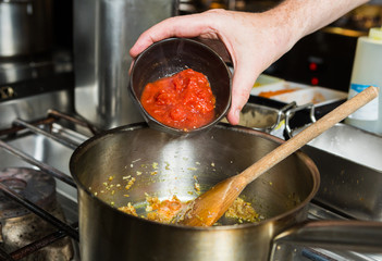 Freshly chopped organic vine ripened tomatoes, being dropped into a hot frying pan as part of a recipe stage.