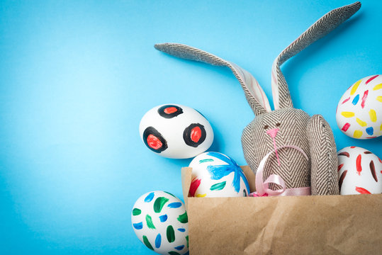Easter bunny in a paper bag. Blue background. Easter ideas. Easter eggs. Space for text.
