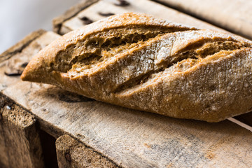 Rye whole wheat bread roll with golden crust on wood vintage box