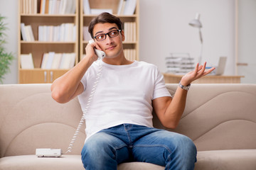 Young man talking on the phone lying in couch