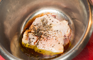 An organic, free range raw duck fillet, being marinated in a metal mixing bowl.