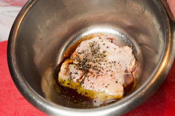 An organic, free range raw duck fillet, being marinated in a metal mixing bowl.