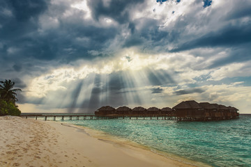 Heaven sun rays over water bungalows at tropical island resort