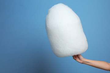 Female hand holding cotton candy on blue background