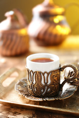 Turkish tea in cup with holder on metal tray closeup
