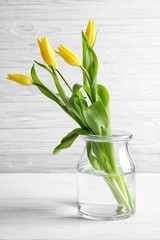 Glass vase with bouquet of beautiful tulips on color background