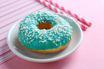 Tasty glazed donut with coconut flakes on plate, closeup