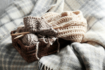 Fototapeta na wymiar Knitting yarn and needles in wicker basket on plaid