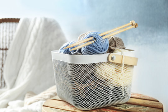 Plastic box with knitting yarn and needles on stool