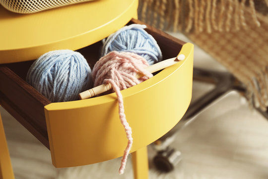 Knitting yarn and hook in yellow table drawer, closeup