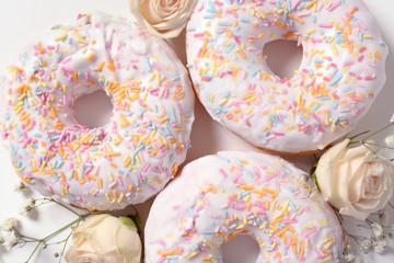 Delicious doughnuts and beautiful flowers, closeup
