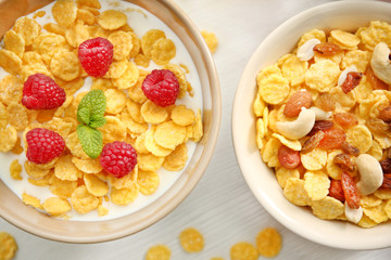 Tasty cornflakes with raspberries, raisins and nuts on table