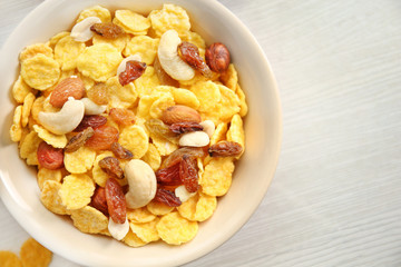 Tasty cornflakes with nuts and raisins on table