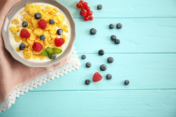 Tasty cornflakes with raspberries and blueberries on blue background