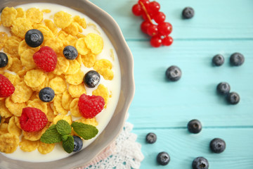 Tasty cornflakes with raspberries and blueberries on blue background