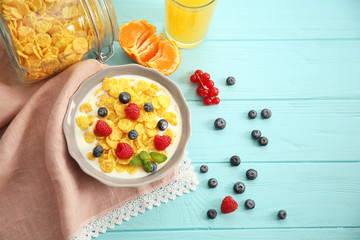 Tasty cornflakes with raspberries and blueberries on blue background