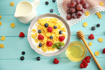 Tasty cornflakes with raspberries and blueberries on blue background