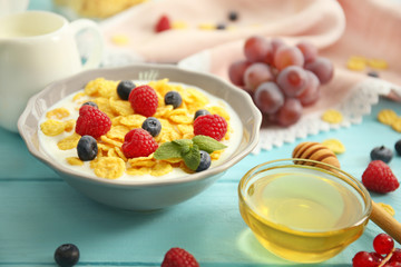 Tasty cornflakes with raspberries and blueberries on blue background