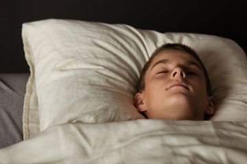 Boy asleep in bed with head on pillow