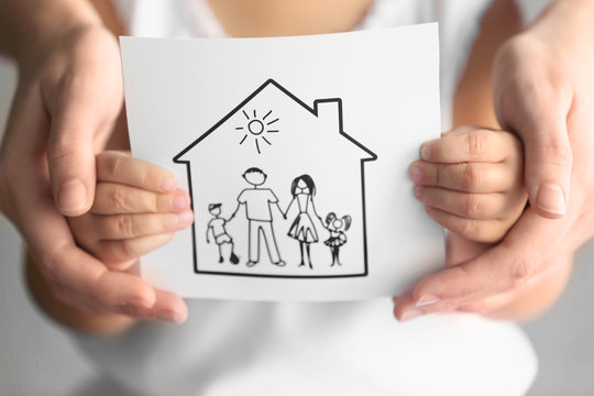 Child and adult person holding drawing of house with family, closeup. Adoption concept