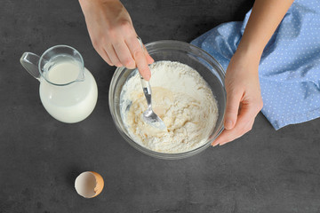 Female hands preparing dough on kitchen table