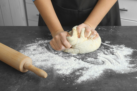 Woman kneading dough on kitchen table, close up
