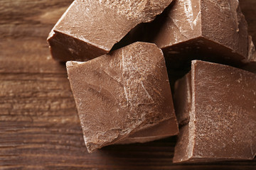 Chocolate pieces on wooden background, closeup