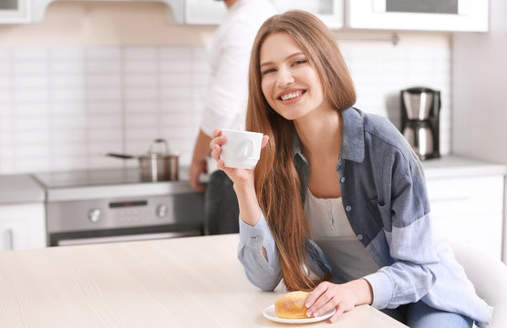 Beautiful Young Woman Drinking Coffee In Kitchen At Home