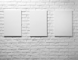 Empty canvases on white brick wall background