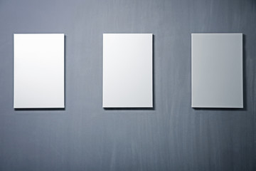 Empty white canvases on gray wall background