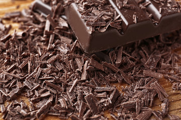 Broken chocolate pieces and shavings on table, closeup