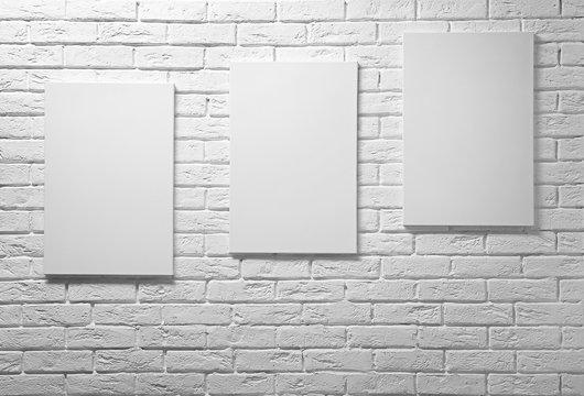 Empty canvases on white brick wall background