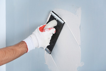 Hand of worker making repair in room